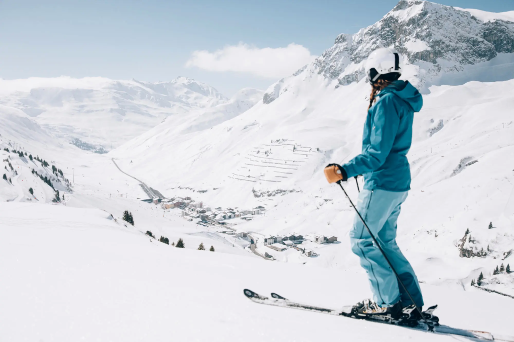 Panoramablick auf das winterliche Lech – Skifahrerin auf der Piste