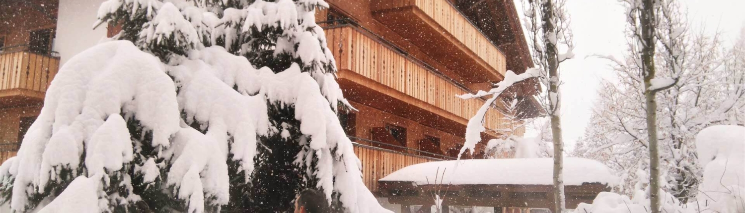 Entspannung pur im Winter – ein Gast genießt den beheizten Außenpool, während sanft der Schnee auf das Hotel Theodul und die verschneiten Tannen fällt