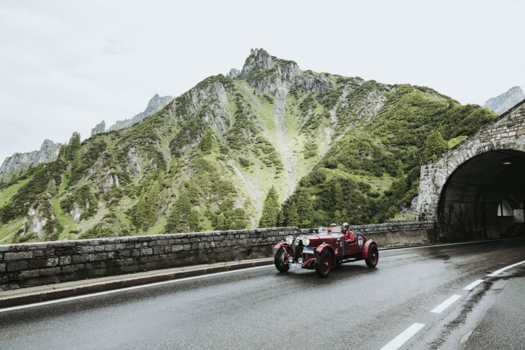 Ein Oldtimer fährt durch die beeindruckende Berglandschaft rund um Lech – ein Stück Nostalgie auf kurvigen Alpenstraßen.
